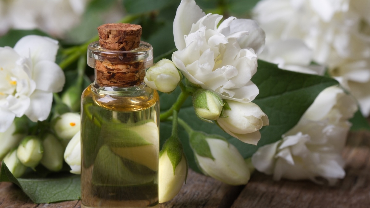 A bottle of jasmine essential oil for menopause next to white flowers