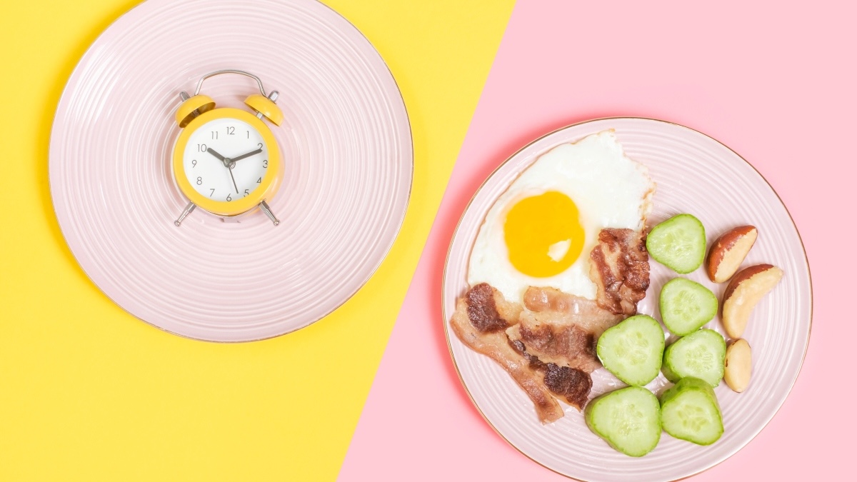 A plate with a clock (to illustrate fasting to lose belly fat) and a plate with food