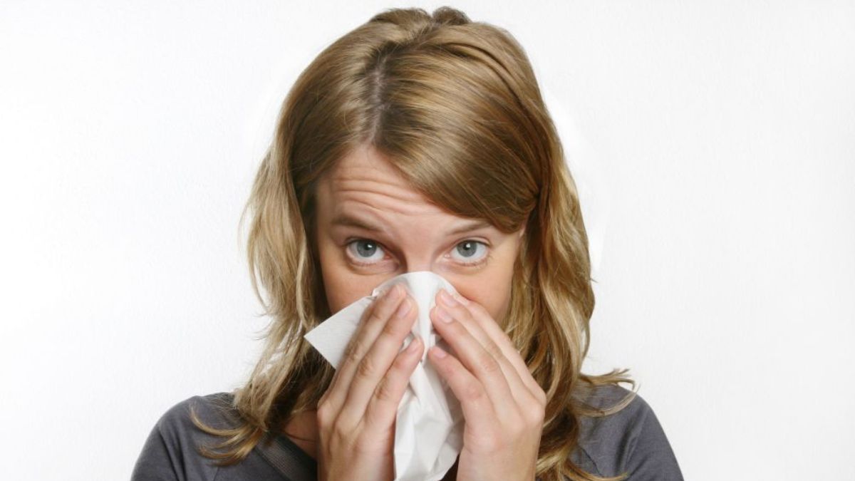 Woman with the flu blowing her nose
