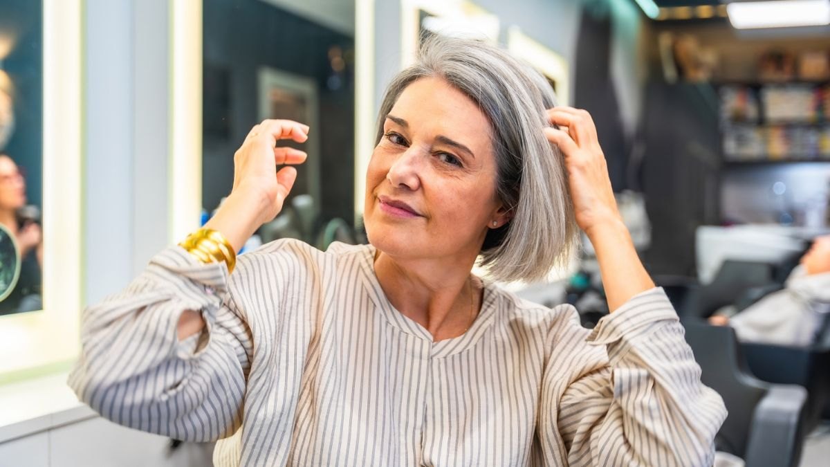 Woman in menopause adjusting her hair in a mirror