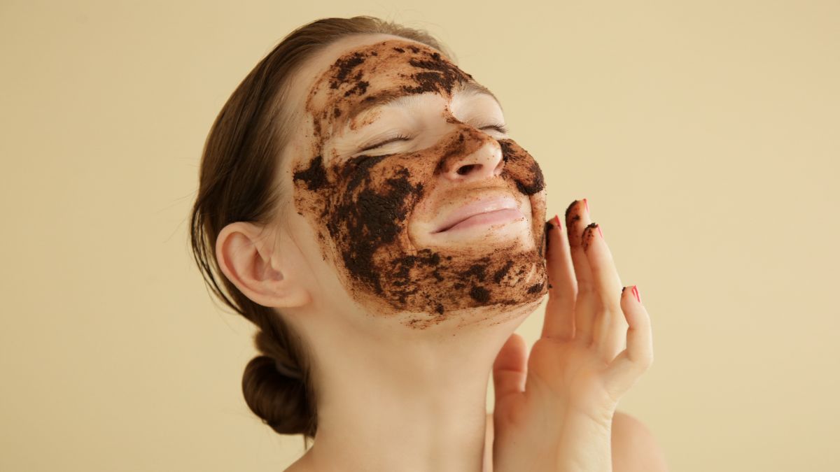 Beautiful woman applying coffee scrub on face