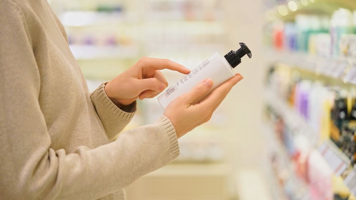 Close-up of female customer holding a cosmetic bottle and reading the label