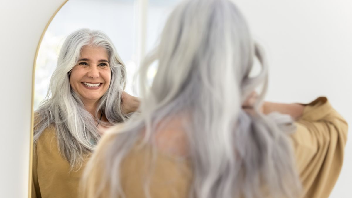 Happy positive elderly Hispanic woman mirror reflection and back view