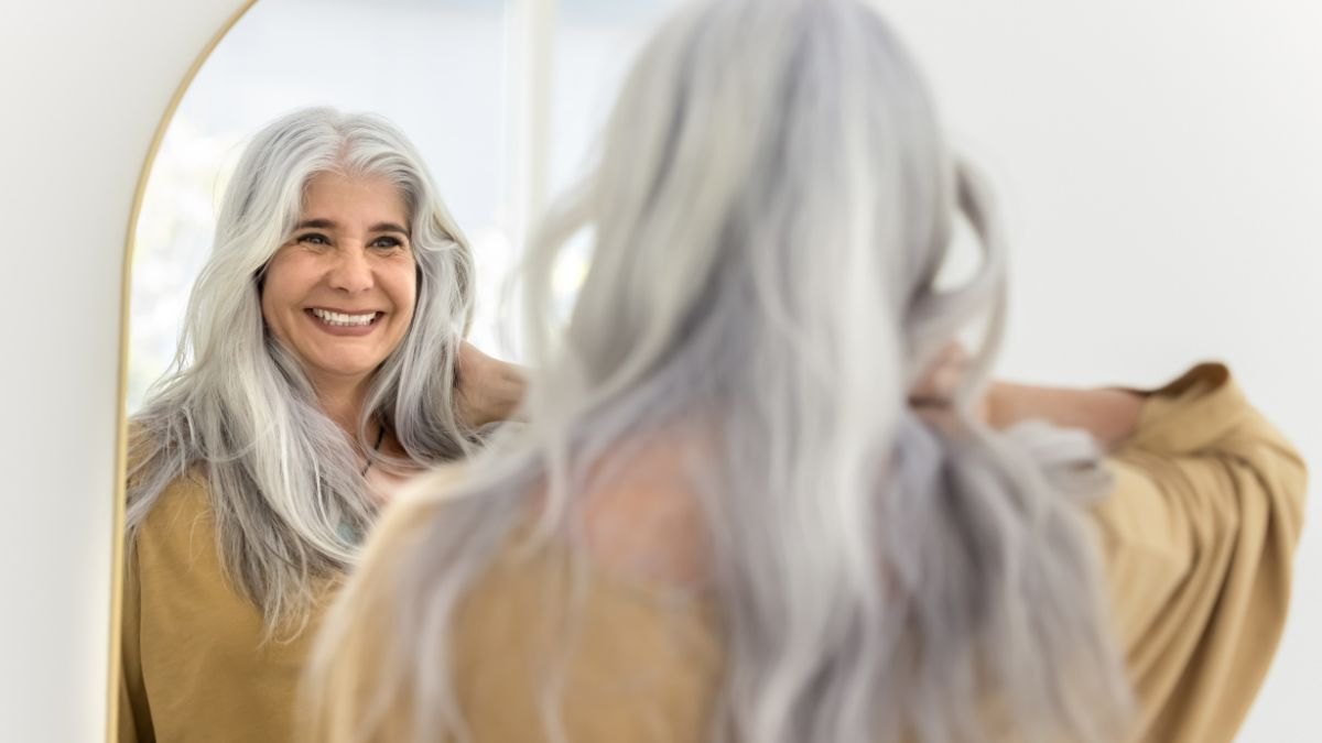 Happy positive elderly Hispanic woman mirror reflection and back view