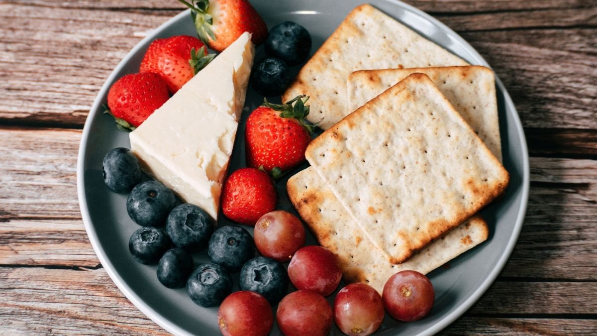 Plate of crackers, cheese and berries, all of which are ideal bedtime snacks for heartburn