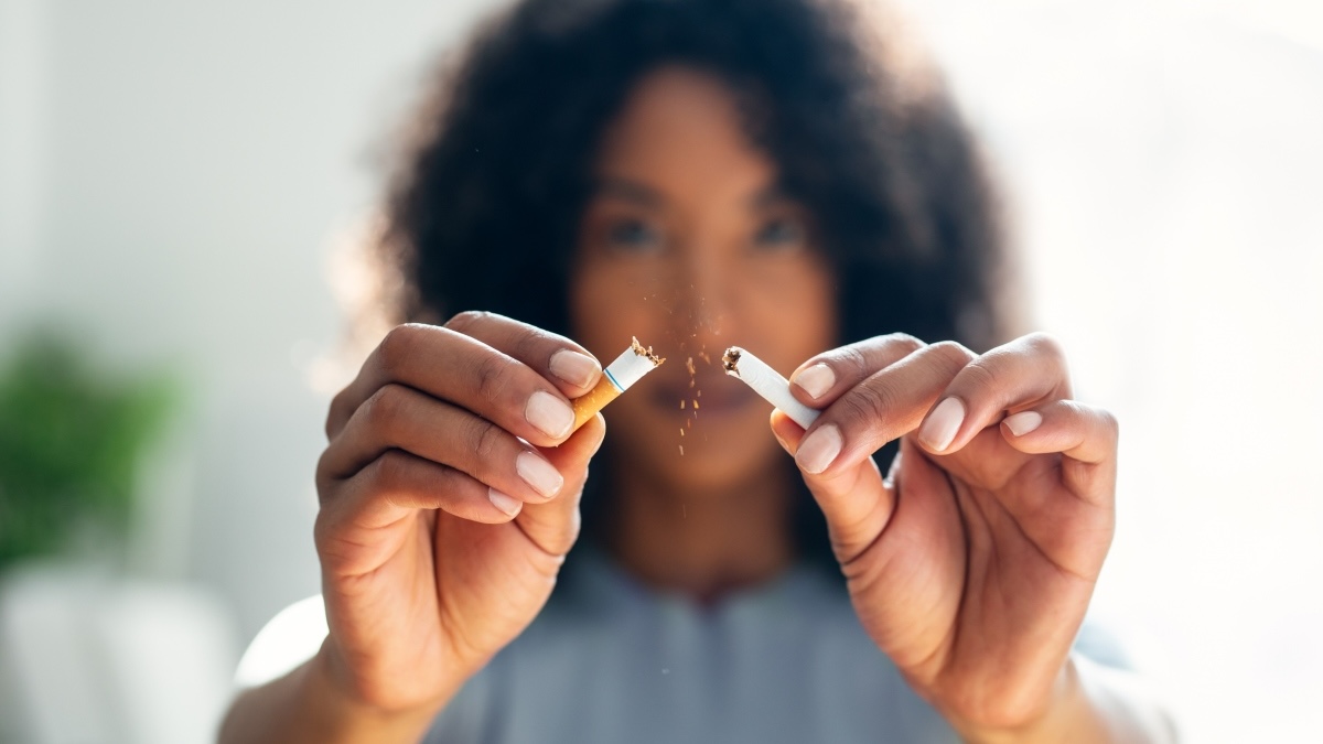 A woman breaking a cigarette in half to quit smoking