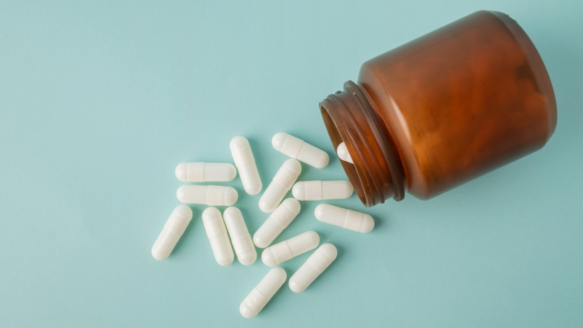 NMN supplement bottle with white pills against a pale turquoise background