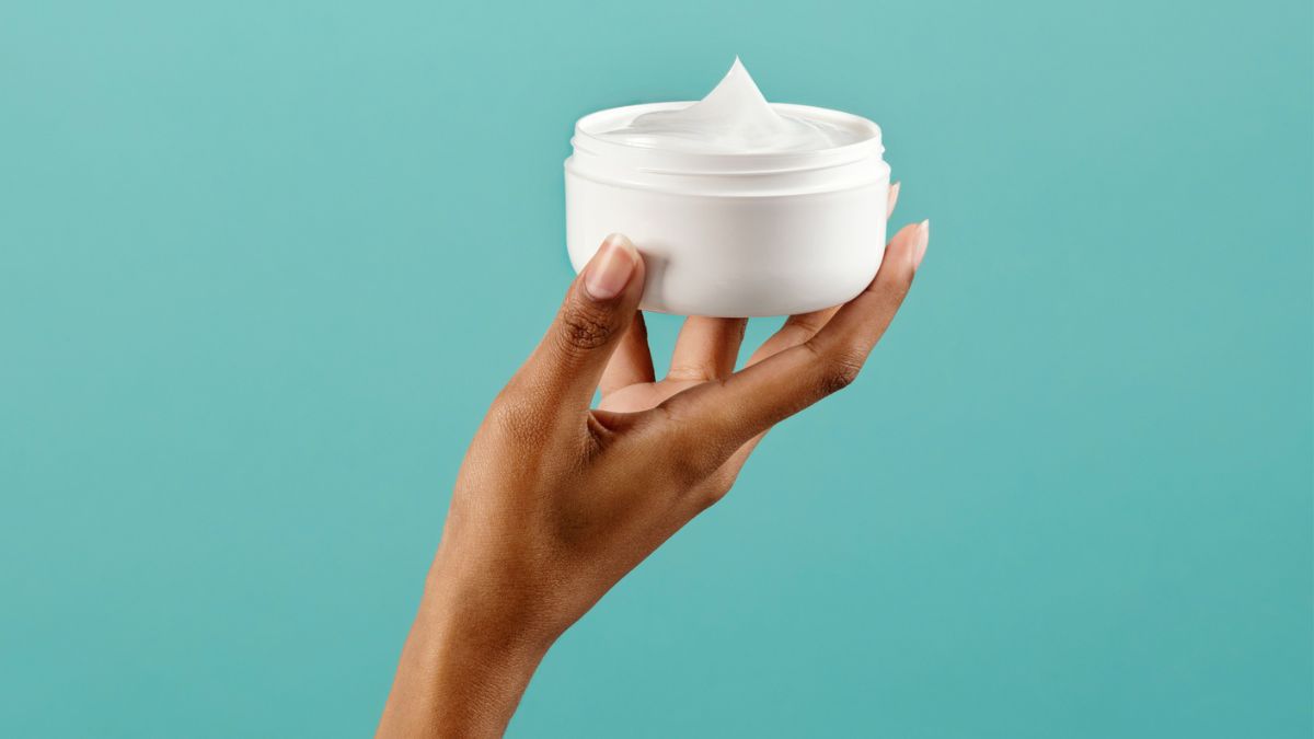 Woman's hand holding jar of cream to treat vaginal dryness